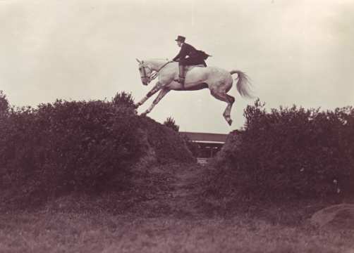 1931 Irmgard von Opel überwindet mit ihrem Schimmelhengst „Nanuk“ den Großen Wall. Die herausragende Amazone prägte nicht nur in Aachen das Turniergeschehen. 1934 sollte sie als erste Frau das Deutsche Derby in Hamburg gewinnen. 