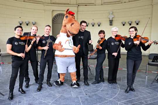 CHIO Aachen-Maskottchen Karli (4.v.l.) mit Aachens Generalmusikdirektor Christopher Ward und Musikern des Sinfonieorchesters Aachen. Foto: CHIO Aachen/ Andreas Steindl