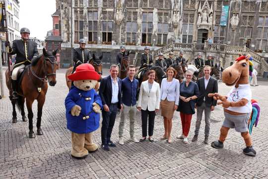 The participants of the press conference with the two mascots Karli (r.) and Paddington (l.) in front of members of the Aachen City Riders. From left to right: Michael Mronz, Gerrit Nieberg, Birgit Rosenberg, Stefanie Peters, Sibylle Keupen and Sönke Rothenberger. Photo: CHIO Aachen/Andreas Steindl