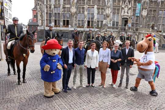 Das Foto zeigt die Teilnehmer der Pressekonferenz mit den beiden Maskottchen Karli (r.) und Paddington (l.) vor Mitgliedern der Aachener Stadtreiter. Von links nach rechts: Michael Mronz, Gerrit Nieberg, Birgit Rosenberg, Stefanie Peters, Sibylle Keupen und Sönke Rothenberger. Foto: CHIO Aachen/Andreas Steindl