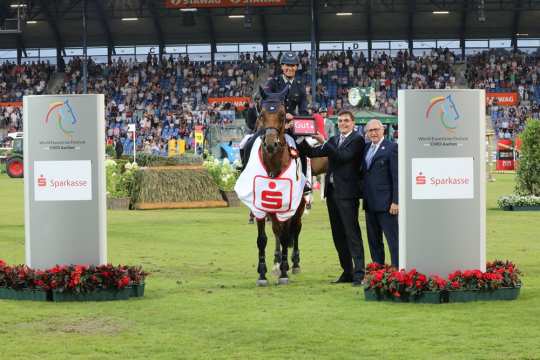 The winner is congratulated by Norbert Laufs, chairman of Sparkasse Aachen, and ALRV Supervisory Board member Wolfgang "Tim" Hammer. 