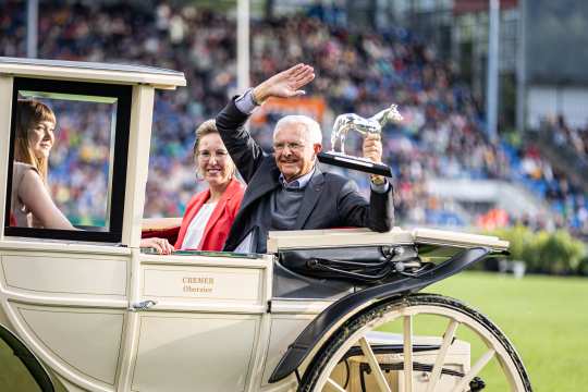 Sieger des Medienpreises Silbernes Pferd Christoph Hess mit den anderen beiden Podiumsplatzierten in einer altmodischen beigen Pferdekutsche werden nach der Siegerehrung durch das ausverkaufte Hauptstadion gefahren.