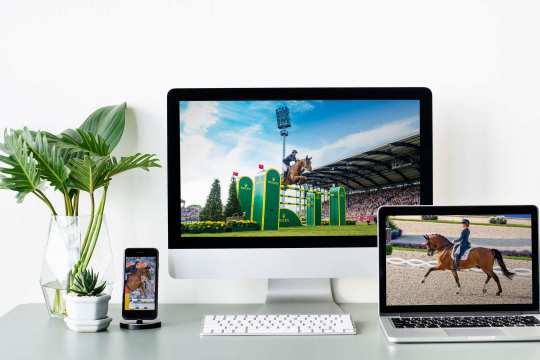 Das Bild zeigt einen Computer, einen Laptop und ein Smartphone auf einem Schreibtisch.