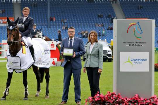 Herr Dr. Tim Grüttemeier, Städteregionsrat der Städteregion Aachen, und ALRV-Präsidentin Stefanie Peters gratulieren dem glücklichen Sieger. Foto: CHIO Aachen/Michael Strauch