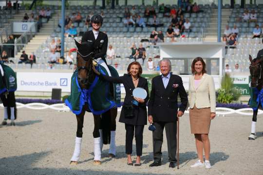   From left: Ms. Marina Meggle, deputy Chairwoman of the Management Board of the Toni Meggle Foundation, Mr. Toni Meggle, Chairman of the Management Board of the Toni Meggle Foundation, and ALRV President Stefanie Peters congratulate the winner in the Deutsche Bank Stadium. Photo: CHIO Aachen / Michael Strauch