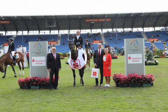 From left: Supervisory board member Wolfgang "Tim" Hammer and Ralf Wagemann, board member of Sparkasse Aachen, congratulate the winner. Photo: CHIO Aachen / Michael Strauch