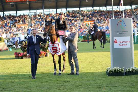 ALRV-Aufsichtsratsmitglied Dr. Thomas Förl und Norbert Laufs, Vorstandsvorsitzender der Sparkasse Aachen, gratulieren dem Sieger. Foto: CHIO Aachen/Michael Strauch