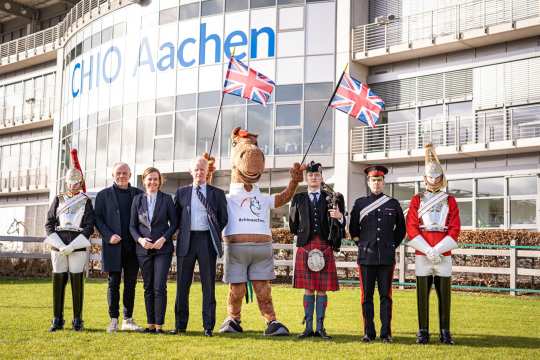 Das Foto zeigt Vertreter des Partnerlandes Großbritannien, des CHIO Aachen und Maskottchen Karli. Eingerahmt von Guards des Household Cavalry Regiments von links nach rechts: Uwe Brandt, Birgit Rosenberg, Jim Eyre, Karli, Dudelsackspieler David Johnston und Daniel Evans. Foto: CHIO Aachen/ Jil Haak