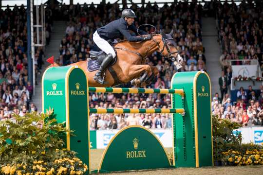 Andre Thieme und seine Fuchstute Chakaria fliegen über den grün gelben Rolex Spung vor der gespannten Zuschauermenge