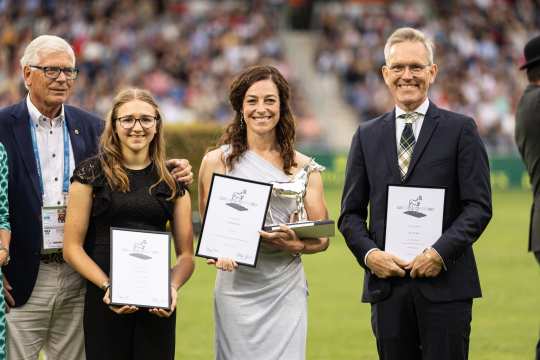 Das Bild zeigt drei Gewinner des Preises "das silberne Pferd" und einen Herrn etwas dahinter stehend. Die drei Gewinner sind zwei Frauen und ein Mann.