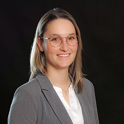 Das Bild zeigt die Mitarbeiterin Julie Spronck in weißer Bluse mit grauem Blazer.
