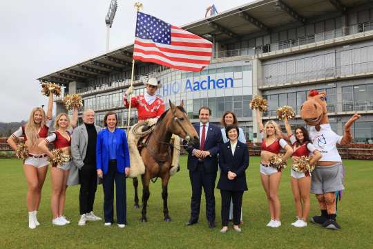 The photo shows the protagonists of the press conference on the occasion of the presentation of the partner country at the CHIO Aachen 2024. Framed by cheerleaders from the Rhine Fire Düsseldorf and CHIO Aachen mascot Karli from right to left: US Consul General Pauline Kao, ALRV President Stefanie Peters, Head of the NRW State Chancellery Nathanael Liminski, Western rider Josh Clemens on his Quarterhorse, ALRV Board Member Birgit Rosenberg and Opening Ceremony Director Uwe Brandt (Photo: CHIO Aachen/Andreas Steindl).  
