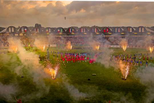 Eine Weitwinkelaufnahme des ausverkauften Hauptstadions bei der Eröffnungsfeier mit Cheerleadern in der Mitte und Feuerwerk drumherum.