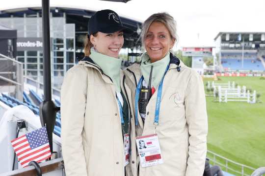 Zwei Ordner in beige-grüner Ordner-Funktionskleidung mit CHIO Aachen Logo, ausgestattet mit Funkgeräten auf der NetAachen-Tribüne des noch leeren Hauptstadions