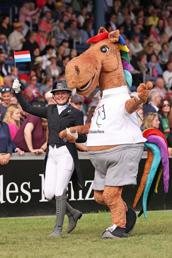 Maskottchen Karli und Dressurreiterin Fie Christina Skarsoe laufen Hand in Hand durchs Hauptstadion beim Abschied der Nationen.