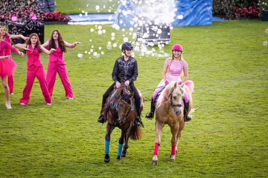 Hella Gabbert im pinken Outfit auf einem Palomino rechts und Julia Steinbrecher im Western Outfit auf einem braunen Pferd links reiten parallel zu einander bei der Öffnungsfeier durch das Hauptstadion.