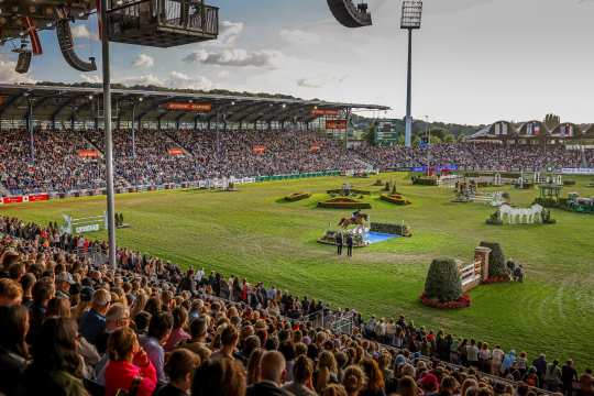 Bild vom vollen Hauptstadion während ein Pferd über den Wassergraben springt.
