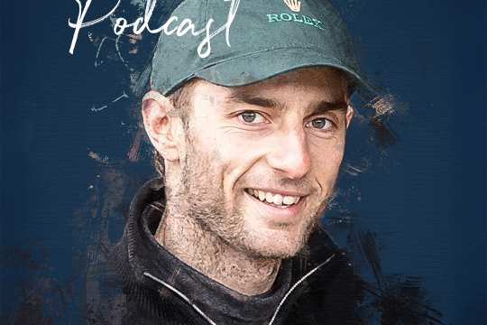 CHIO Aachen podcast cover of Richard Vogel in a painterly style with black and dark green brushstrokes on the contours of his smiling portrait. He is wearing a dark knitted jumper with a half-open zip of the stand-up collar as well as a green cap with the Rolex logo.