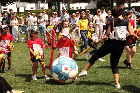 At Soers Sunday on the jumping arena, lots of children play with a big football in yellow and red outfits.