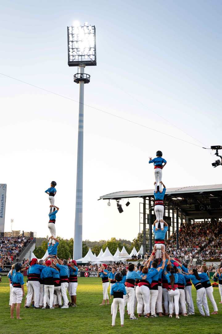 Two human towers in blue and white costumes at the opening ceremony in the main stadium.