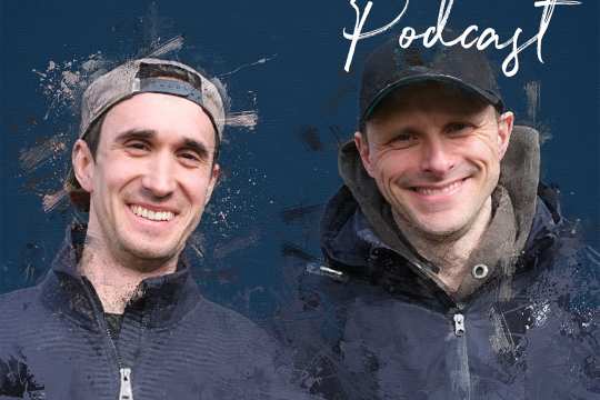 Podcast-Cover „CHIO Aachen Podcast“ mit zwei lächelnden Männern in dunklen Jacken und Caps vor blauem Hintergrund; unten links ist ein kleines CHIO-Aachen-Logo zu sehen.