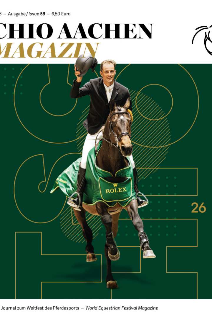 Cover of the “CHIO AACHEN MAGAZINE” 2026, issue 59: A show jumper in a light riding jacket approaches the viewer on a brown horse wearing a green ROLEX winner’s blanket, smiling and raising his riding helmet in the air. The background is dark green with large graphic line elements and the yellow number “26”. At the top are title, year, issue and price information; at the bottom the subtitle “Das Journal zum Weltfest des Pferdesports – World Equestrian Festival Magazine” and a stylized horse-head logo.