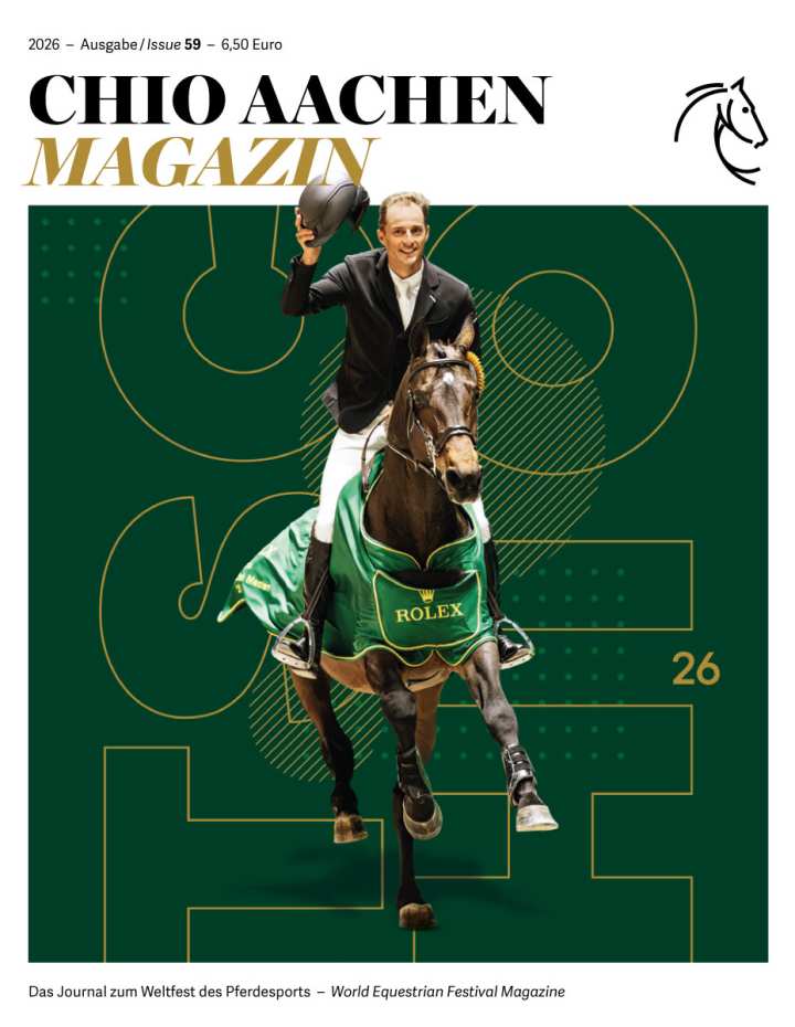Titelblatt des „CHIO AACHEN MAGAZIN“ 2026, Ausgabe 59: Ein Springreiter in hellem Jackett reitet auf einem braunen Pferd im grünen ROLEX-Siegersattelpad direkt auf den Betrachter zu und hebt lächelnd seinen Reithelm. Der Hintergrund ist dunkelgrün mit großen, grafischen Linien und der gelben Zahl „26“. Oben stehen Titel, Jahrgang, Ausgaben- und Preisangabe, unten der Untertitel „Das Journal zum Weltfest des Pferdesports – World Equestrian Festival Magazine“ sowie ein stilisiertes Pferdekopf-Logo.